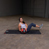 Woman doing sit ups with exercise ball on workout mat medicine ball red and black body solid