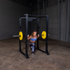 woman doing lunges on body solid power rack barbell and yellow bumper plates