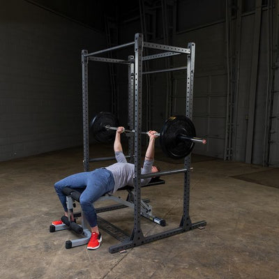 man doing bench press on squat rack by powerline