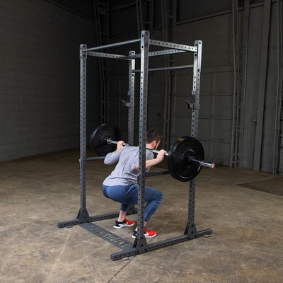 man doing squats on powerline squat rack