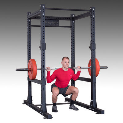 Commercial power rack SPR1000 guy doing back squats with bumper plates